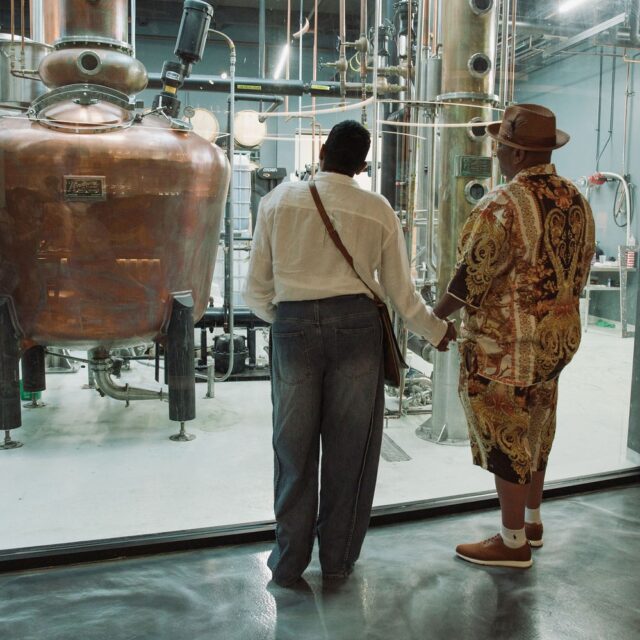 couple holding hands near distillery stills