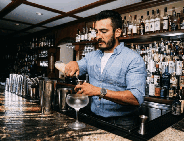 Adam Morgan pours ingredient into jigger behind bar